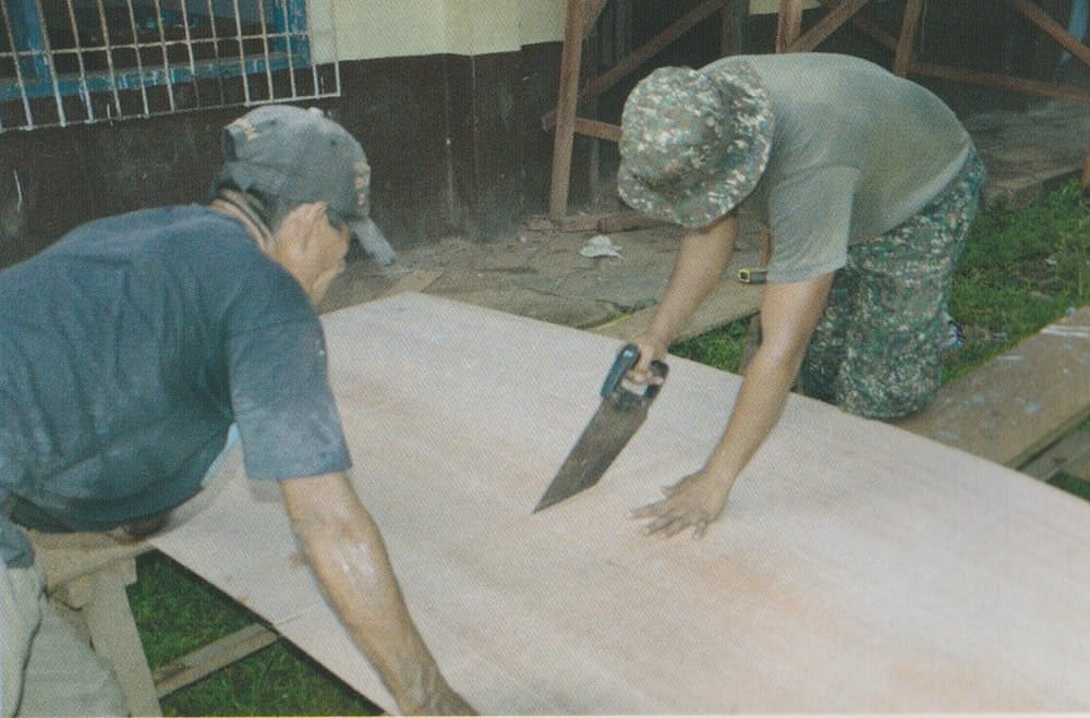 A Marine helping a civilian renovate a classroom during Brigada Eskwela